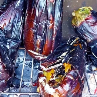 Fresh Eggplants Being Grilled to Perfection on a Barbecue, with Visible Grill Marks and a Smoky Aroma.