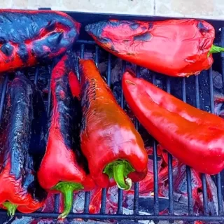 Fresh Peppers Being Grilled on a Barbecue, With Visible Grill Marks and Smoke Rising.