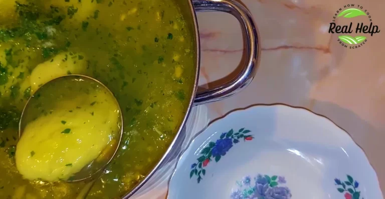 Close-Up of Chicken Dumplings in a Green Broth, Served in a Silver Pot, Next to a Floral-Decorated White Plate.
