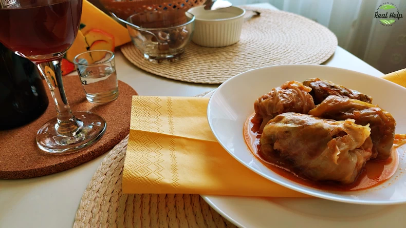 Romanian Cabbage Rolls Neatly Arranged on a Pristine White Plate, Paired With a Glass of Rich Wine.